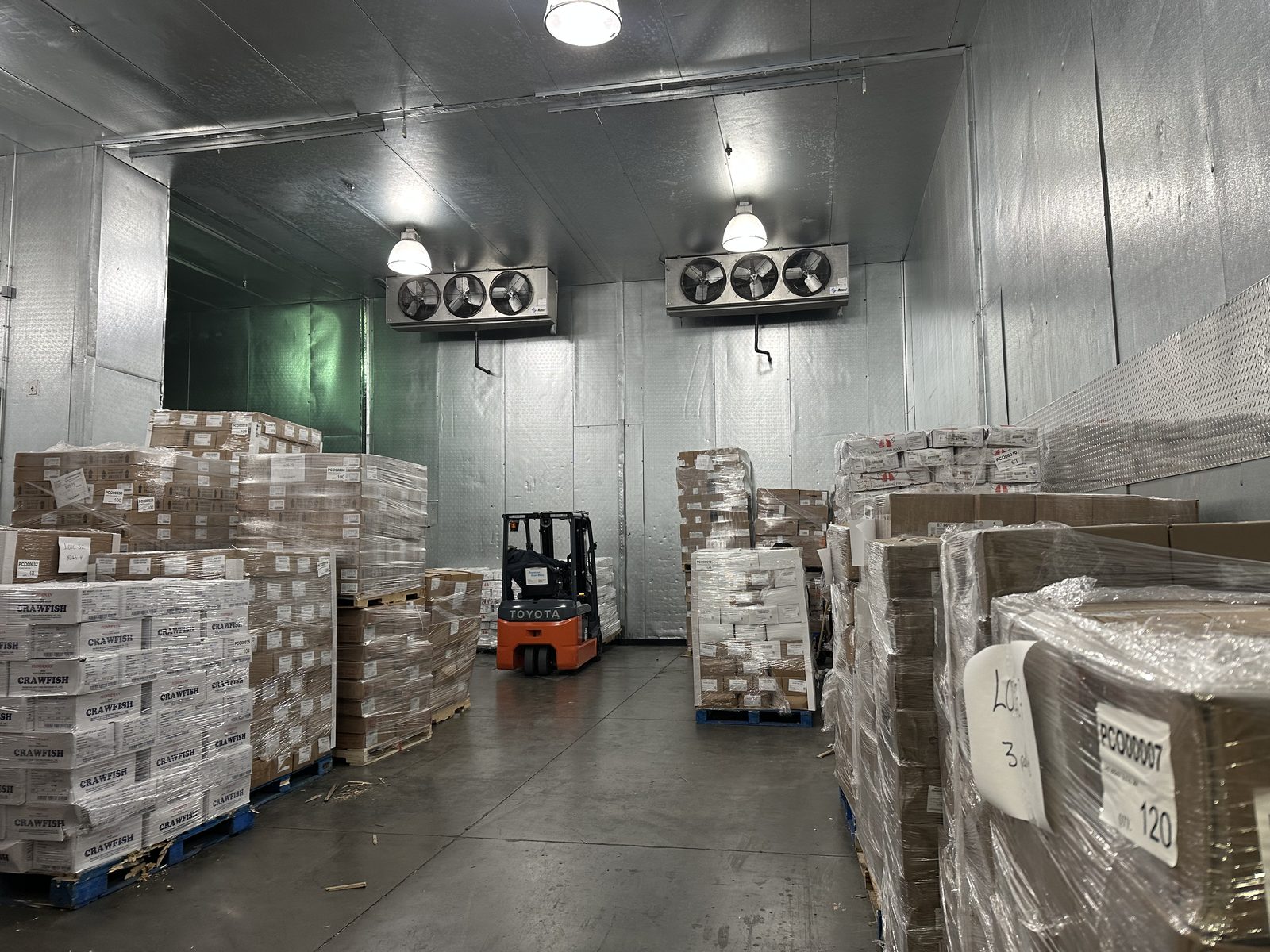 Before installation, frozen product floor-stacked several pallets deep on both sides of a narrow freezer aisle